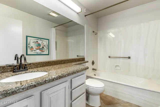 a bathroom with a granite countertop sink mirror vanity and toilet