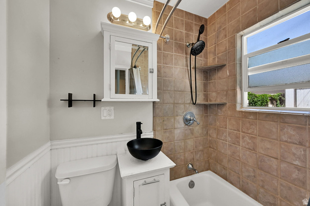 291 800 East Bountiful, UT 84010 - Photo 12 of 20 Bathroom featuring a white vanity with a black vessel sink, a white medicine cabinet with integrated lighting, and a bathtub with tile surround
