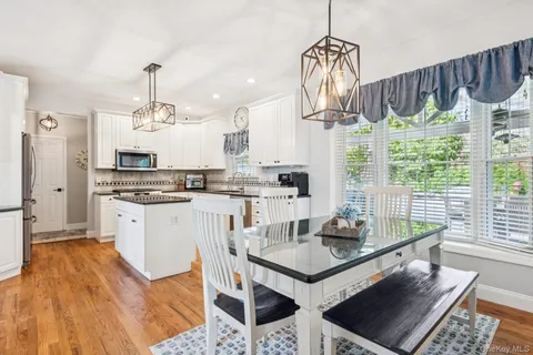 a kitchen with stainless steel appliances granite countertop a stove a sink dishwasher and a dining table with wooden floor