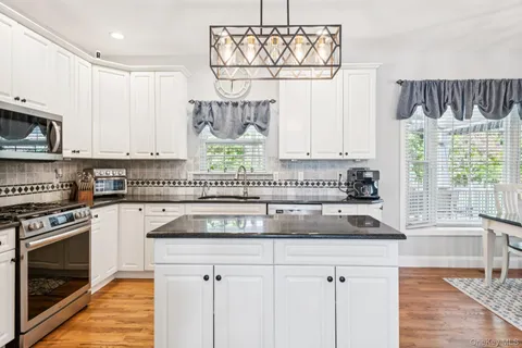 a kitchen with stainless steel appliances granite countertop a stove a sink and a white cabinets