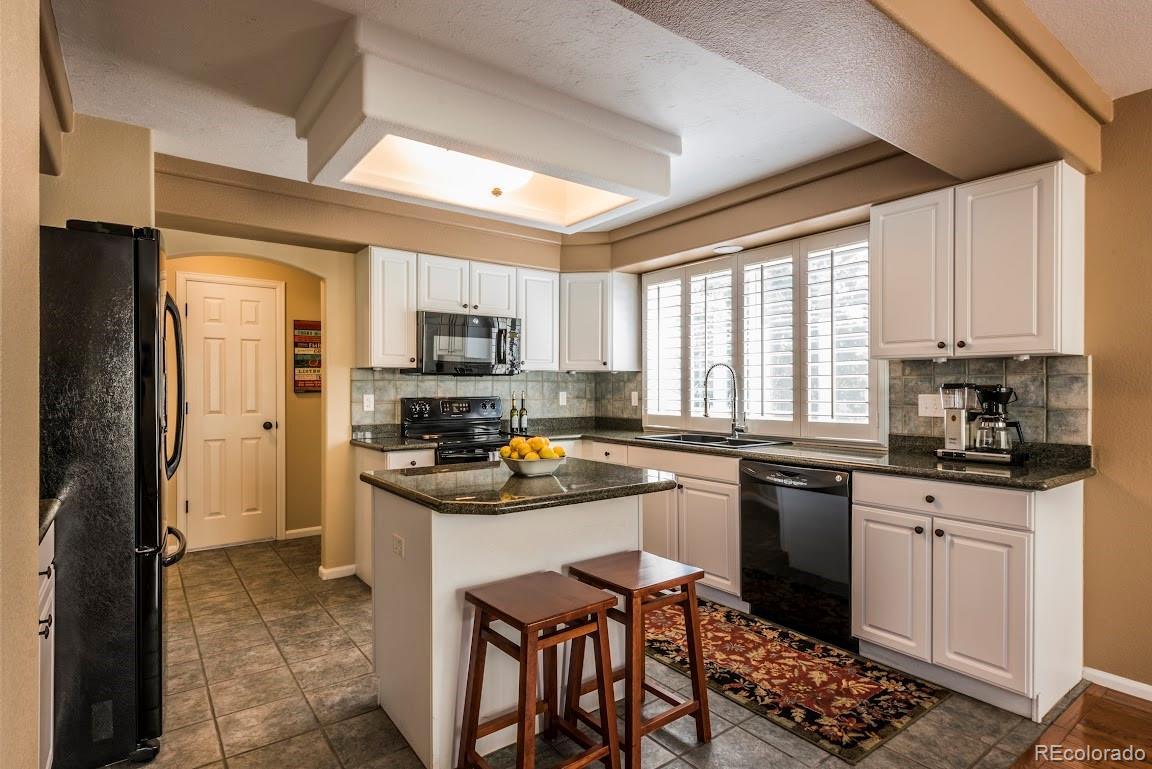 1279 Braewood Avenue Highlands Ranch, CO 80129 - Photo 18 of 20 a kitchen with stainless steel appliances granite countertop a stove top oven a sink dishwasher a dining table and chairs with wooden floor