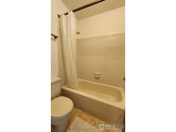 a bathroom with a granite countertop bathtub shower sink vanity and toilet