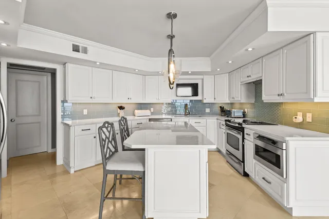 a kitchen with stainless steel appliances granite countertop a stove a sink a microwave a refrigerator a stove a white table and chairs