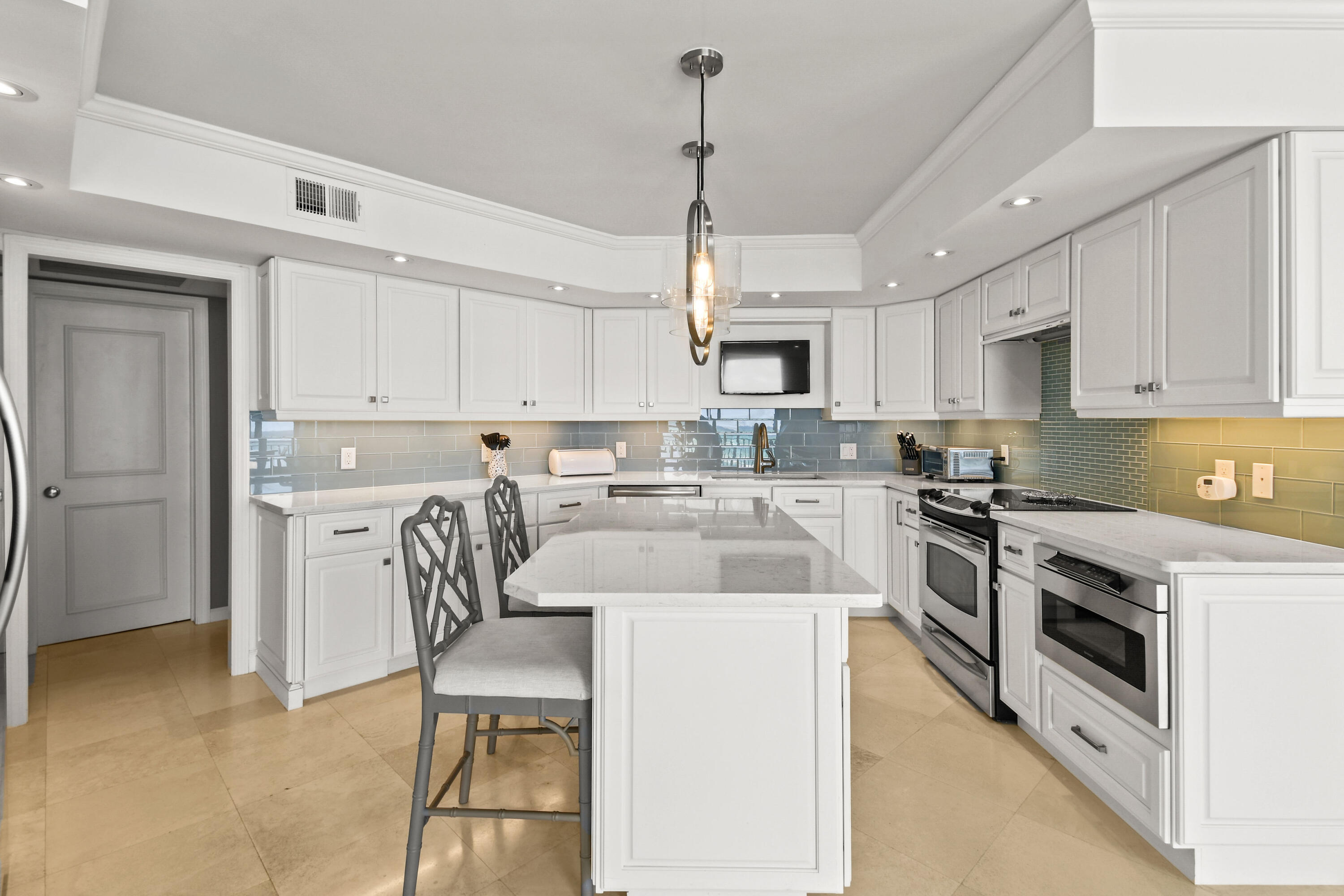 19850 South Beach Road, Unit 5A Jupiter, FL 33469 - Photo 9 of 28 a kitchen with stainless steel appliances granite countertop a stove a sink a microwave a refrigerator a stove a white table and chairs