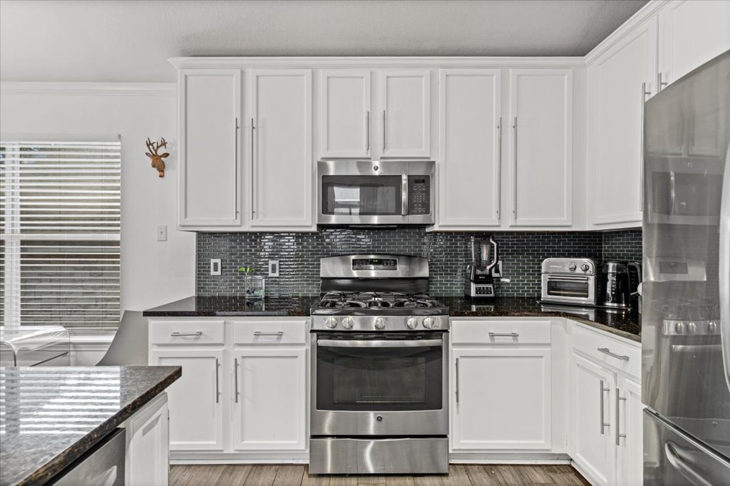 5948 Lomita Verde Circle Austin, TX 78749 - Photo 7 of 31 a kitchen with granite countertop white cabinets and stainless steel appliances