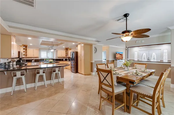 a dining hall with stainless steel appliances kitchen island granite countertop a table chairs and a sink