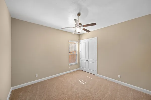 an empty room with windows and fan