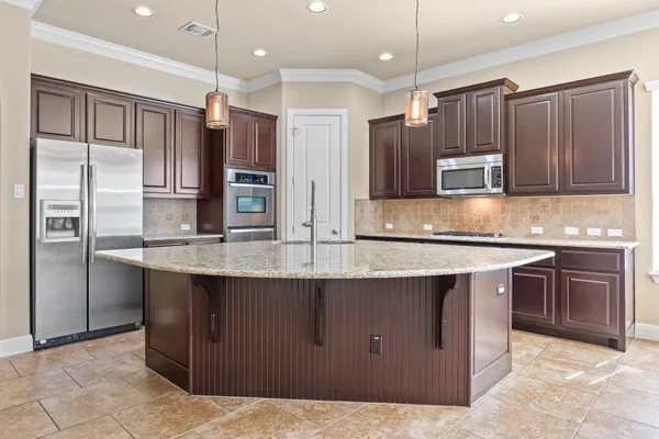 a kitchen with kitchen island granite countertop wooden cabinets a refrigerator and a sink