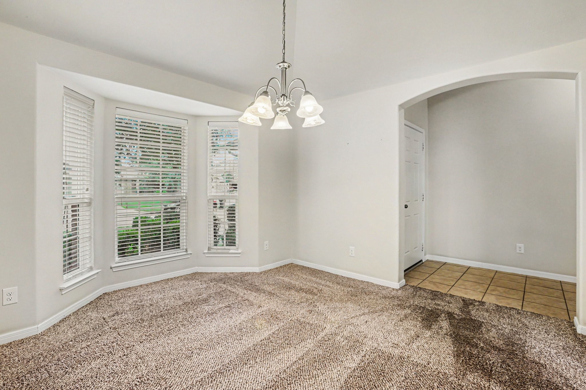 25222 Ginger Ranch Drive Katy, TX 77494 - Photo 17 of 33 Dining room with a bay window providing natural light. It has a ceiling light fixture and leads to a tiled entrance through an arched doorway.