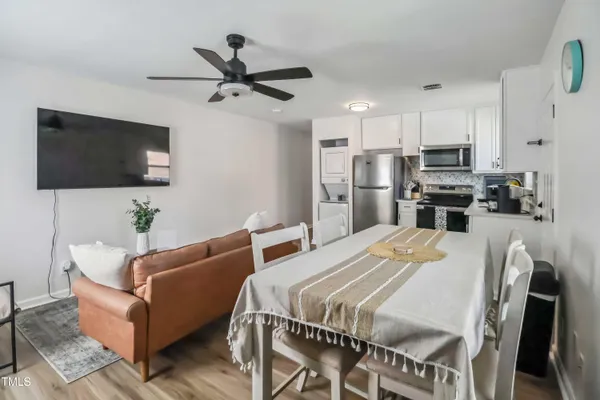 a living room with stainless steel appliances furniture a flat screen tv and a view of kitchen