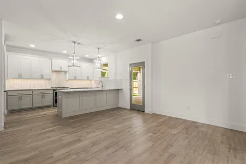 a large white kitchen with a refrigerator a sink dishwasher and a stove with wooden floor