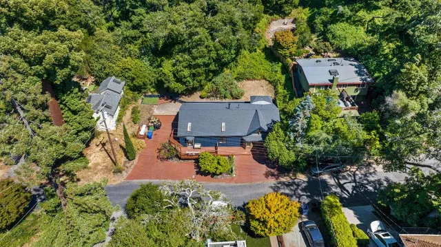 an aerial view of a house with a yard and a large tree
