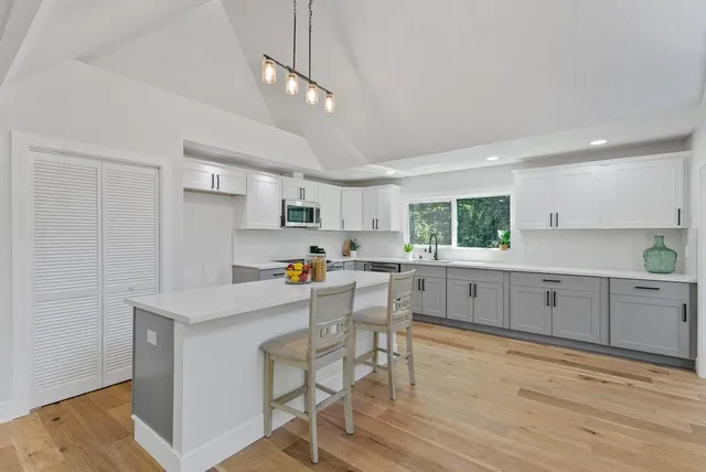 a kitchen with stainless steel appliances a dining table chairs sink and cabinets