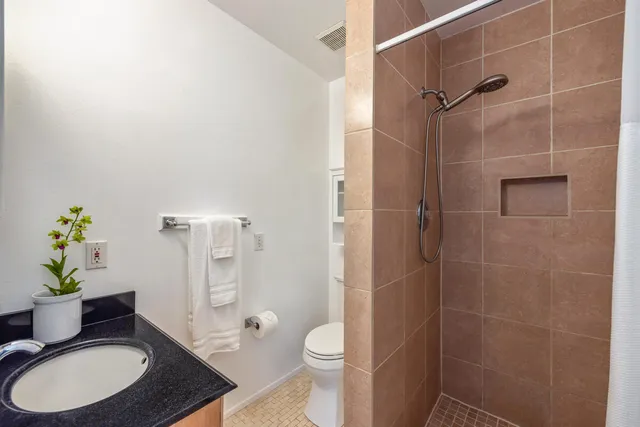 a bathroom with a granite countertop toilet a sink a shower and a mirror