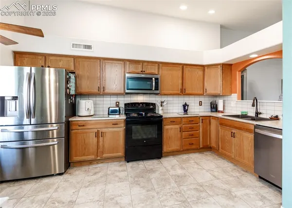 a kitchen with granite countertop a refrigerator stove top oven and sink