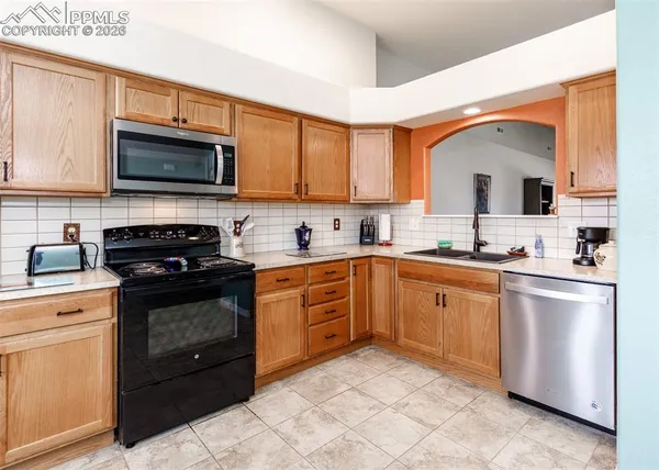 a kitchen with stainless steel appliances granite countertop a stove top oven a sink dishwasher and a microwave oven with large cabinets