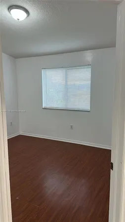 a view of an empty room with wooden floor and closet