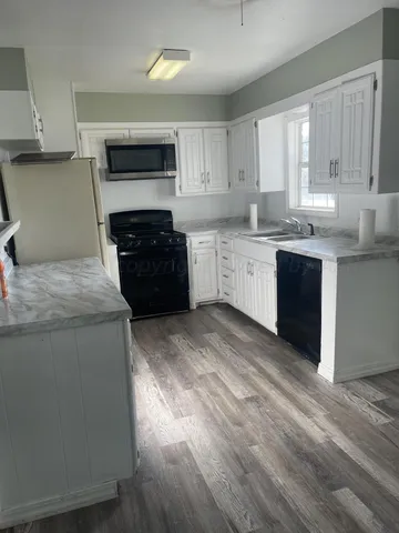 a kitchen with granite countertop a stove top oven sink and cabinets