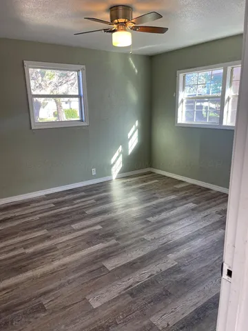 a view of empty room with window and wooden floor