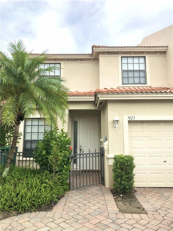 Doorway to property with an attached garage, a tiled roof, stucco siding, and a gate