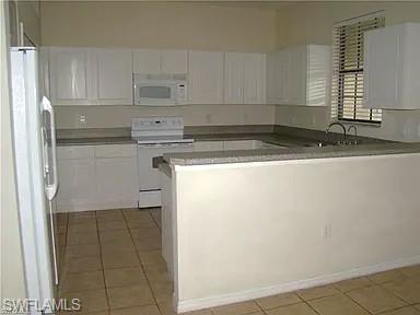 7423 Bristol Circle Naples, FL 34120 - Photo 2 of 6 Kitchen with light tile patterned floors, white appliances, a peninsula, and white cabinetry