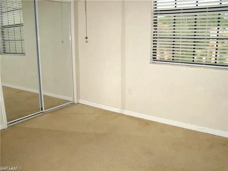 7423 Bristol Circle Naples, FL 34120 - Photo 4 of 6 Unfurnished bedroom featuring carpet, multiple windows, and a closet
