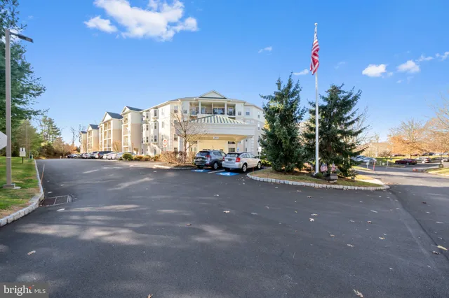 a sign board with flower plants and large trees