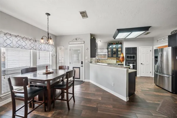 a dining room with stainless steel appliances kitchen island granite countertop a refrigerator a stove a kitchen island with a dining table and chairs