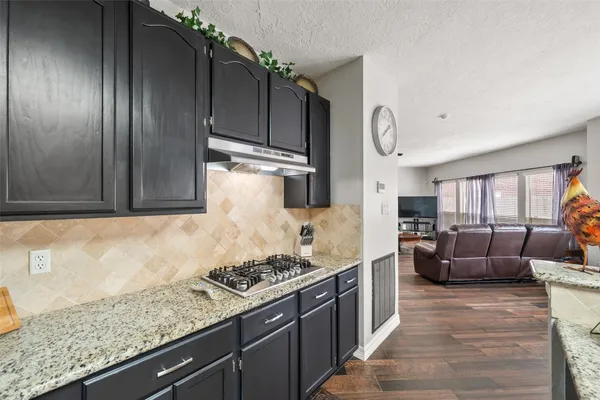 a kitchen with granite countertop a stove and cabinets