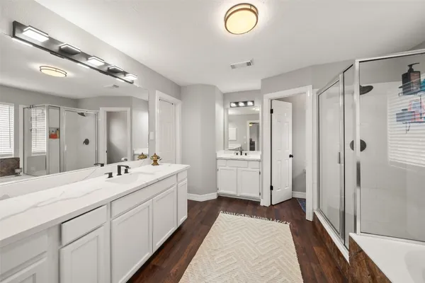 a spacious bathroom with a double vanity sink a mirror and a shower