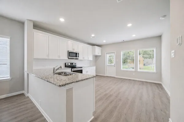 a kitchen with granite countertop appliances a sink and a counter top space
