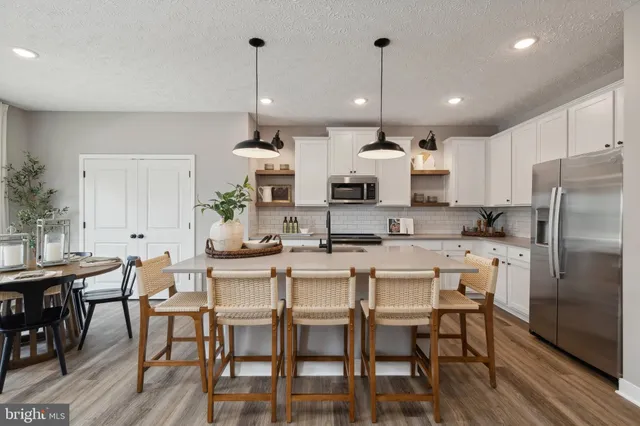 a kitchen with stainless steel appliances kitchen island granite countertop a dining table chairs and white cabinets