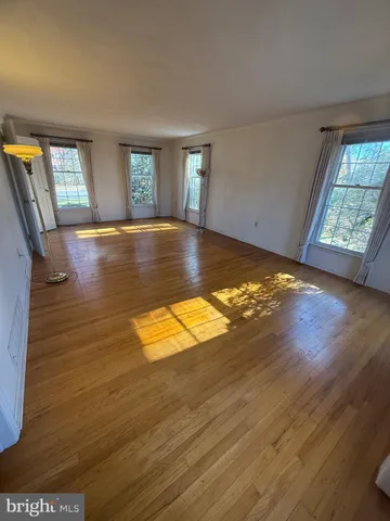 a view of empty room with window and wooden floor