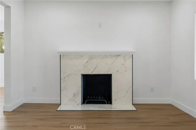 a view of an empty room with wooden floor and a fireplace