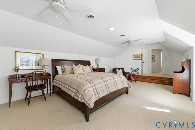 a spacious bedroom with a bed a chair and potted plant on the dresser