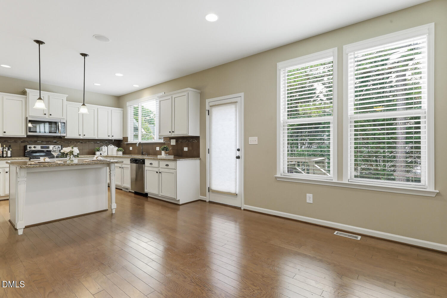 441 Virginia Water Drive Rolesville, NC 27571 - Photo 5 of 20 a kitchen with stainless steel appliances granite countertop a stove a sink a refrigerator and white cabinets with wooden floor