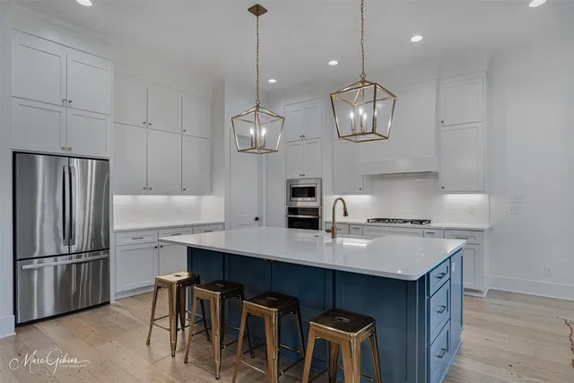 a kitchen with stainless steel appliances a table chairs refrigerator and microwave