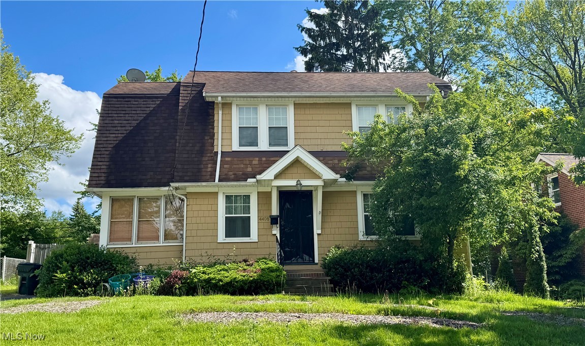 View of front of property with a shingled roof and a front lawn