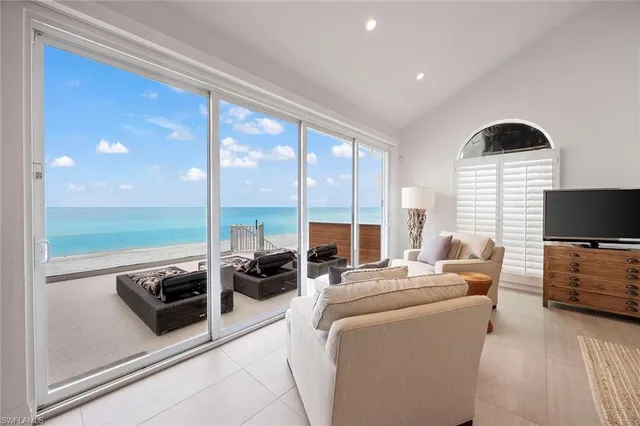 a living room with furniture floor to ceiling window hardwood floor and a flat screen tv