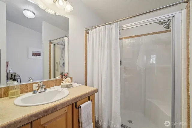 a bathroom with a granite countertop sink a mirror and a shower