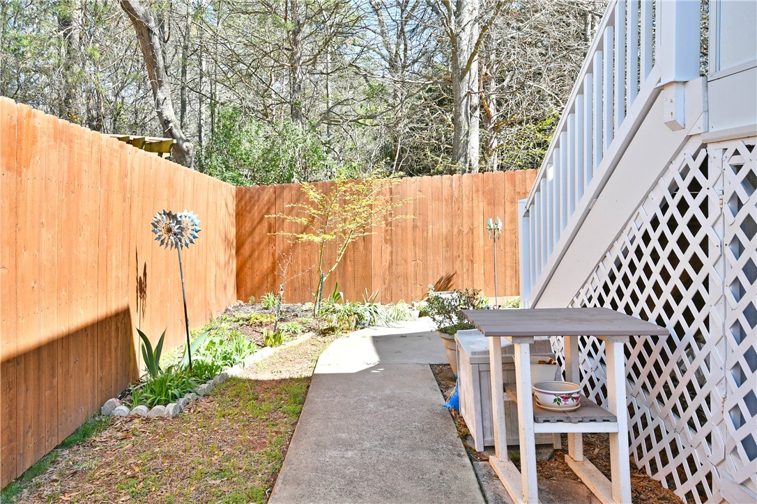 103 Baldwin Place Easley, SC 29642 - Photo 8 of 42 This private yard features a concrete pathway, a wooden fence, and mature trees, perfect for tranquil outdoor moments.