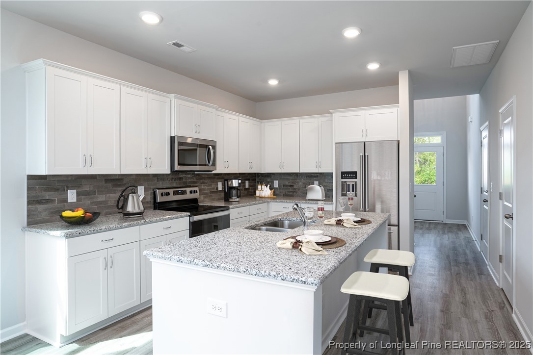 514 Log Pond Road Fayetteville, NC 28311 - Photo 3 of 5 a kitchen with stainless steel appliances kitchen island granite countertop a refrigerator a stove a sink a dining table and chairs