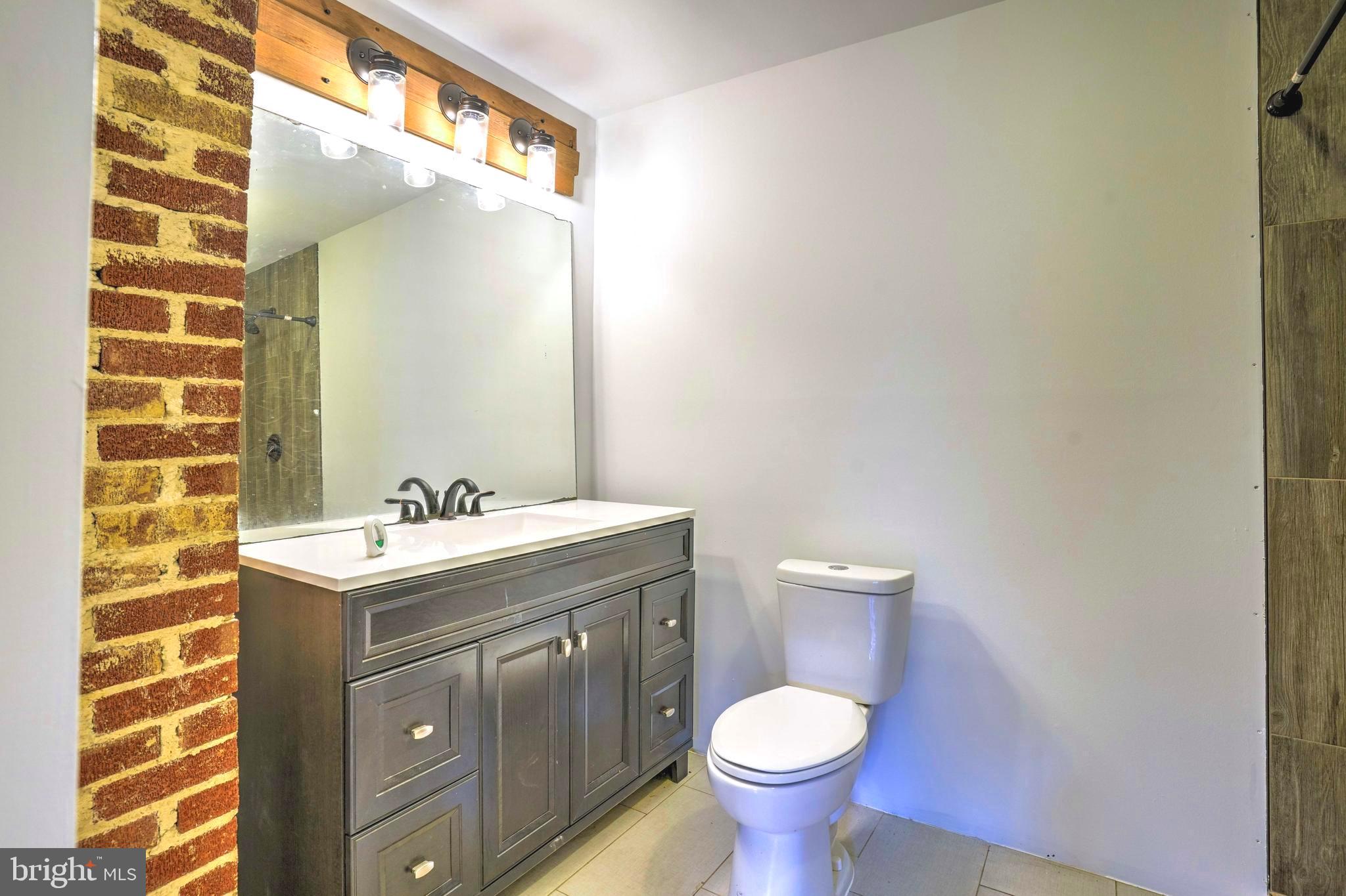 8920 Marshall Corner Road Pomfret, MD 20675 - Photo 13 of 31 a bathroom with a granite countertop toilet a sink and mirror