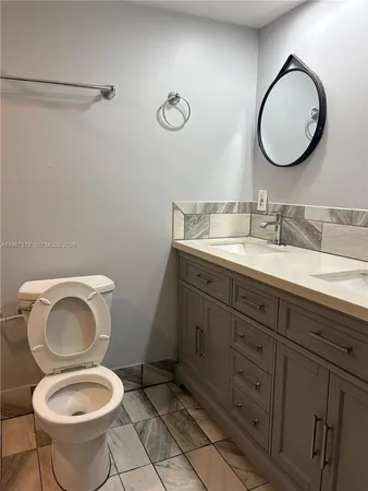 a bathroom with a toilet sink vanity granite and mirror