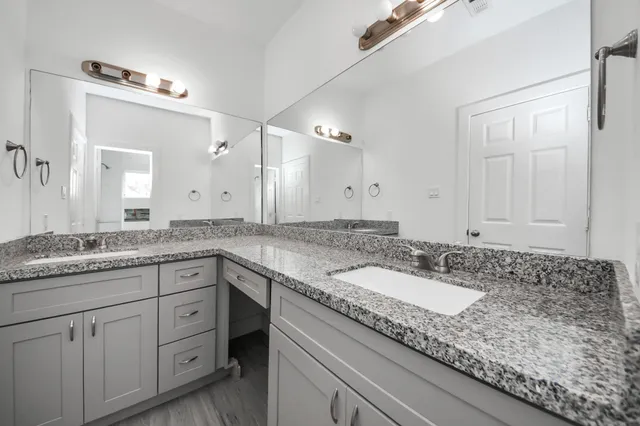 a bathroom with a granite countertop double sink and a mirror