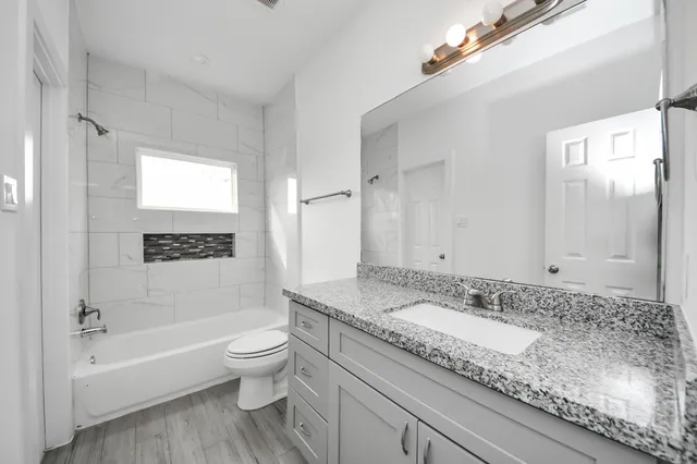 a bathroom with a granite countertop sink a toilet and bathtub