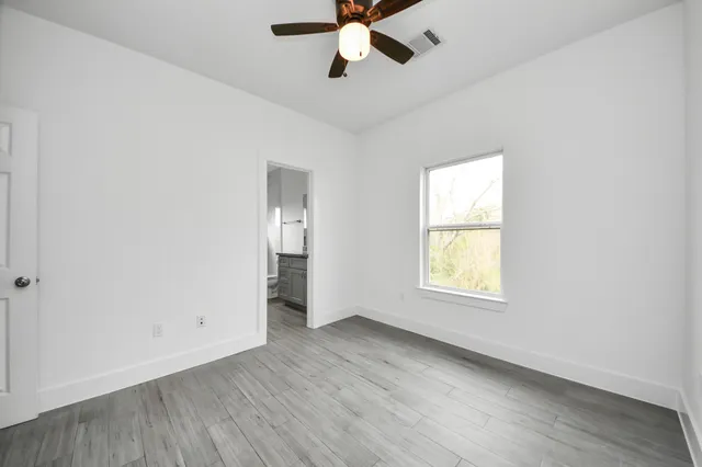 an empty room with wooden floor ceiling fan and windows