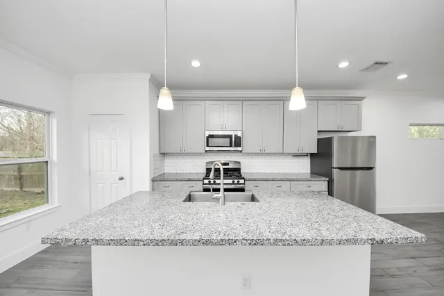 a kitchen with kitchen island granite countertop a sink a counter top space appliances and cabinets