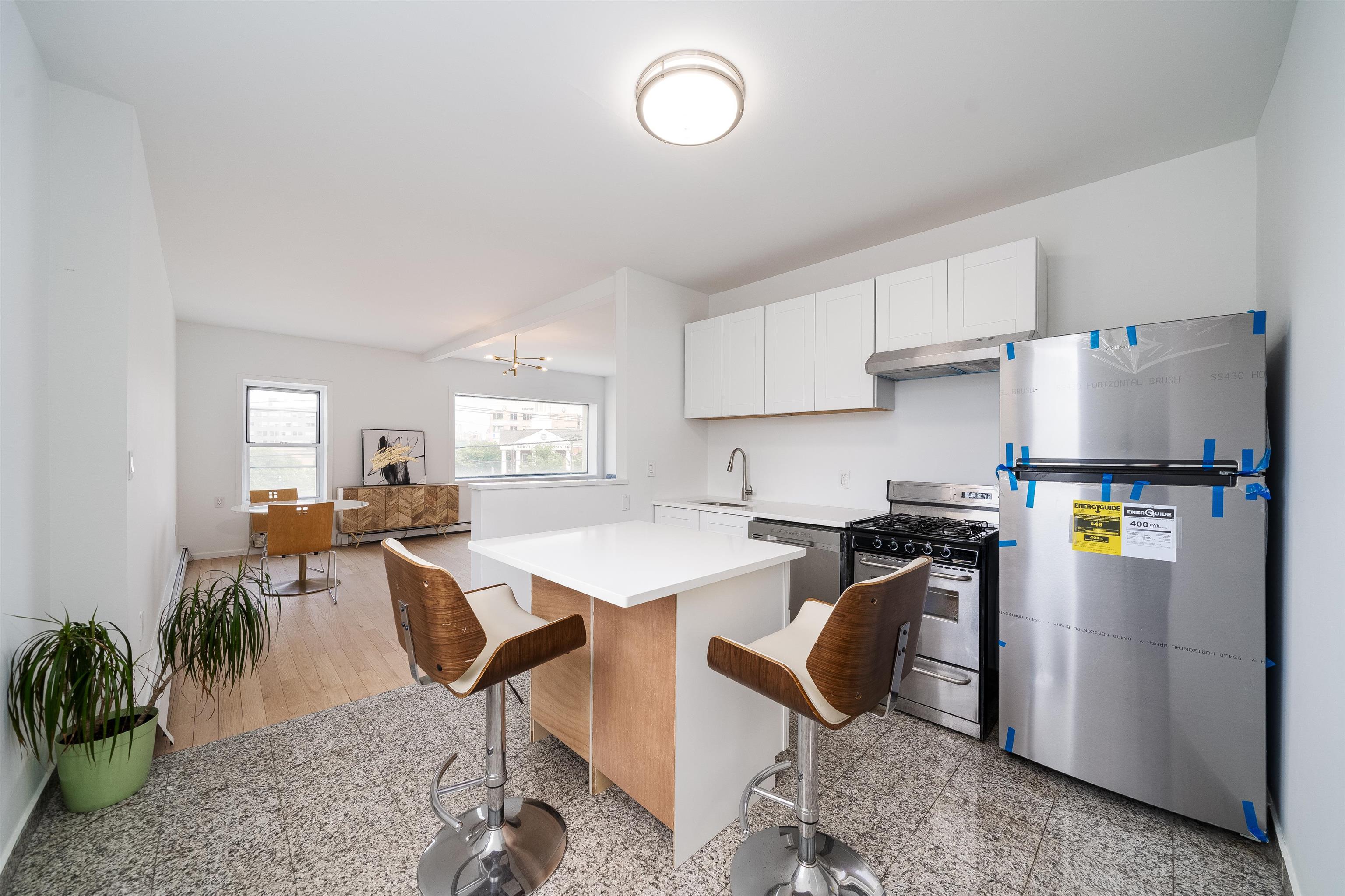a kitchen with stainless steel appliances granite countertop sink stove refrigerator dining table and chairs
