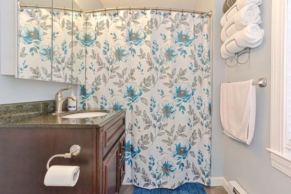 23 Dryden Street Worcester, MA 01605 - Photo 11 of 23 a bathroom with a granite countertop sink a mirror and shower curtain